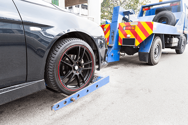 tow truck towing a broken down car on the street 600x400